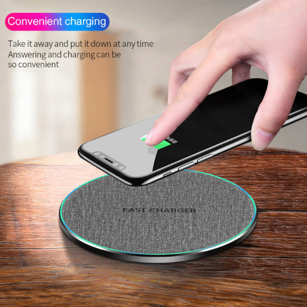 "Hand placing mobile phone on a circular wireless charging dock, emphasizing cable-free convenience and minimalist workspace setup."