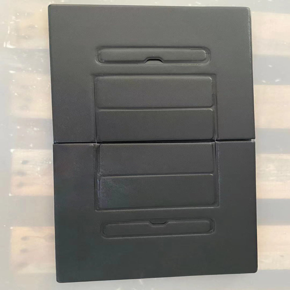 Black rectangular object with cut-out sections on a reflective surface
