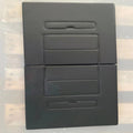 Black rectangular object with cut-out sections on a reflective surface