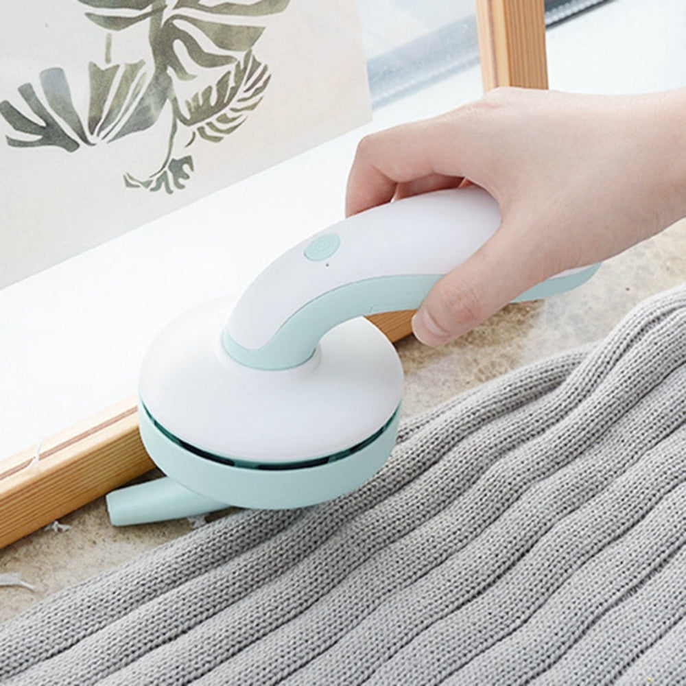 "Portable electric fabric shaver and lint remover in hand, professional garment care gadget on a textured surface with a modern home decor background."
