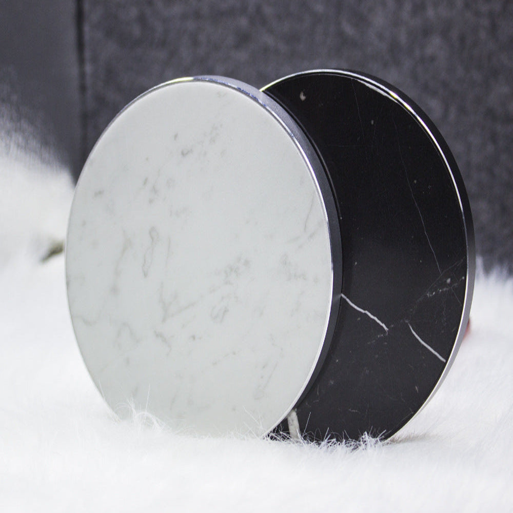 "Pair of marble-patterned circular objects on a neutral textured surface, modern tabletop accessories."