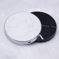 "Two circular electronic devices, one minimalist solid white and one premium black marble-patterned, displayed on a light gray background."