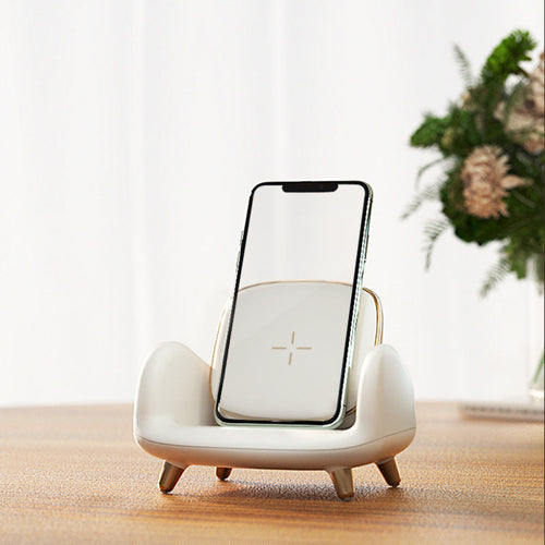 "Sofa-style wireless charger stand with smartphone and blurred floral background"